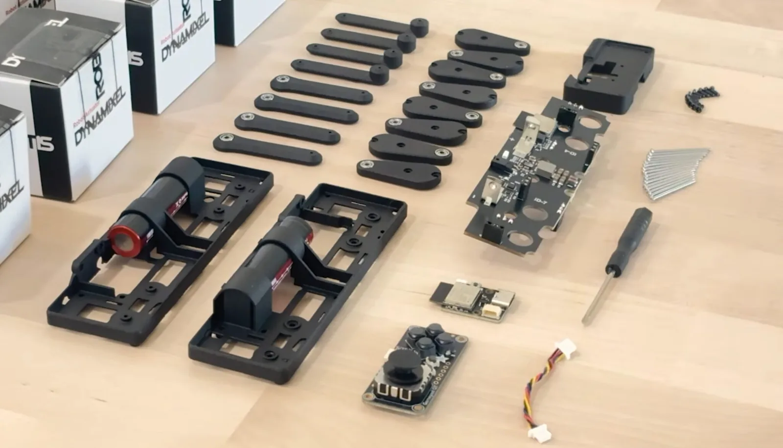 Componentes del kit Q8botOne, con la placa principal, el chasis y las patas impresas en 3D, la placa del control, las baterías y la tornillería. Los actuadores DYNAMIXEL se venden por separado